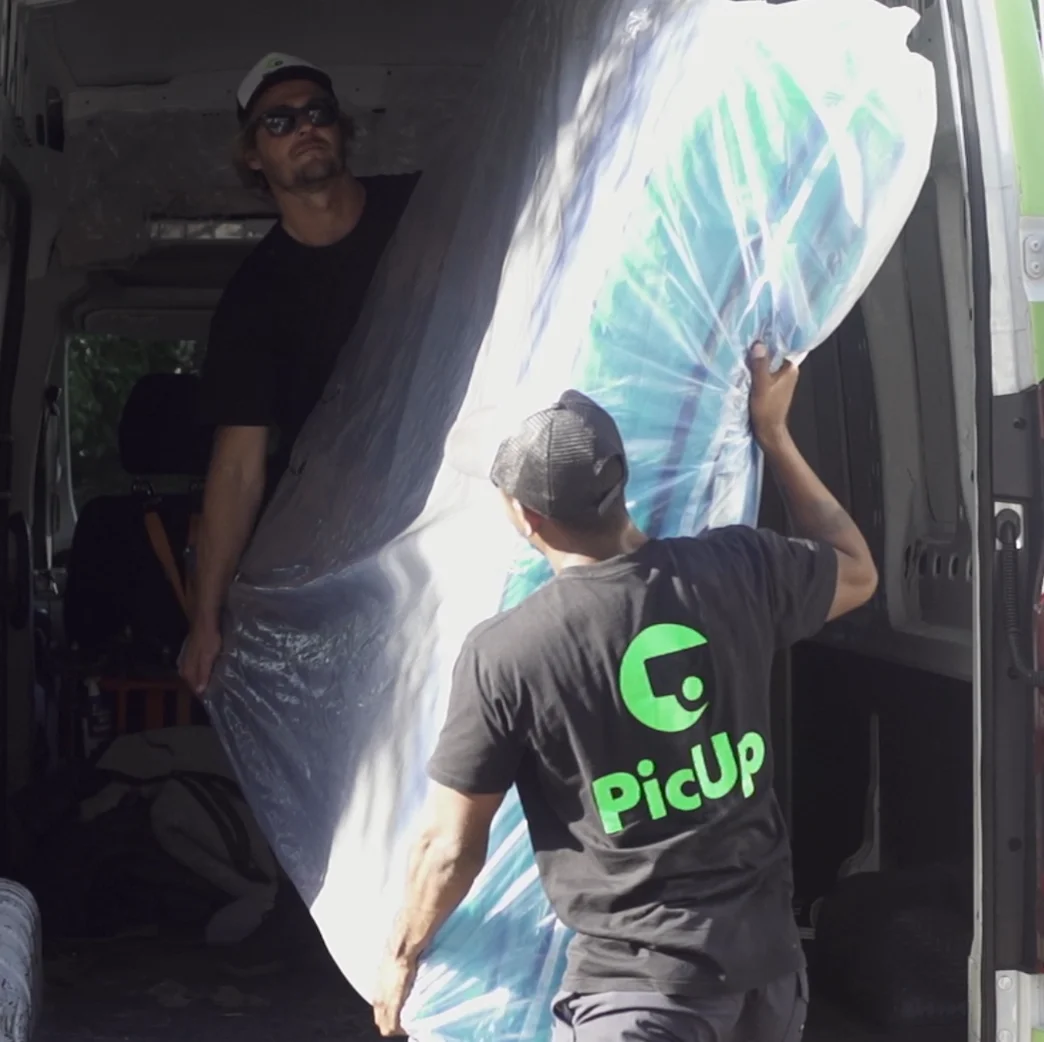 Two PicUp haulers loading a wrapped mattress into a PicUp delivery van